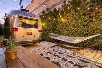 a hammock and a trailer sitting on a patio at Hip Venice Beach Luxury Airstream & Creative Space in Los Angeles