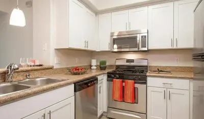 a kitchen with white cabinets and a stove and a microwave at Sunny Marina Del Rey Apartment- Hot Tub, Game Room, BBQ, Projector in Los Angeles
