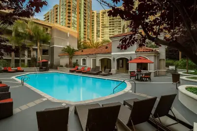 a swimming pool with chairs and a building at Sunny Marina Del Rey Apartment- Hot Tub, Game Room, BBQ, Projector in Los Angeles