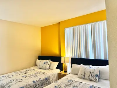 two beds in a room with yellow walls and a window at Cozy and Stylish Unit CC 107 in Los Angeles
