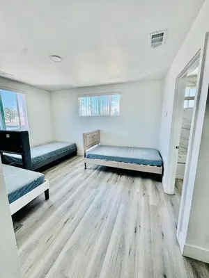 two beds in a room with wooden floors at The Ostel in Los Angeles