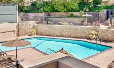 a large swimming pool with an umbrella and chairs and an umbrella at Luxury Pool View Spa Suite-Massage Chair-Steam Sauna-Welcome Champagne ! in Westlake Village