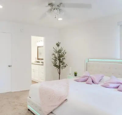 a white bedroom with a bed with pink pillows at Luxury Pool View Spa Suite-Massage Chair-Steam Sauna-Welcome Champagne ! in Westlake Village