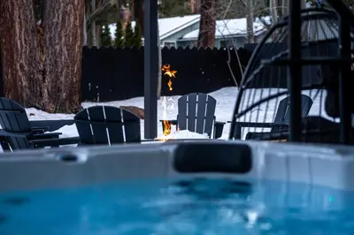 a swimming pool with chairs and a fire in the snow at Summit Haven: Game Room | Sauna | Spa | 1/4 Acre in Big Bear Lake