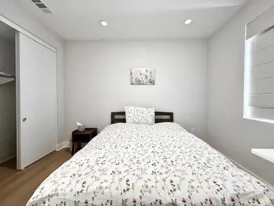 a white bedroom with a bed with a floral bedspread at #Marbella Lane - Spacious 4BR Modern Family Home! in Placentia