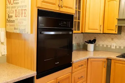a kitchen with a black oven and wooden cabinets at Fullerton Adventure Pad - 10 min to Disneyland in Fullerton