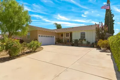 a house with a driveway and an american flag at Fullerton Adventure Pad - 10 min to Disneyland in Fullerton