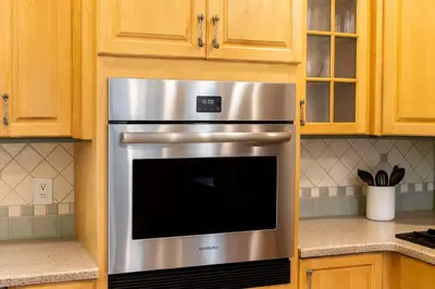 a stainless steel oven in a kitchen with wooden cabinets at Fullerton Adventure Pad - 10 min to Disneyland in Fullerton
