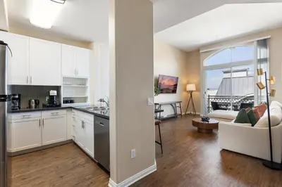 a kitchen with white cabinets and a living room at Serene Zen Peaceful Zen Garden View with Pool Gym in Los Angeles