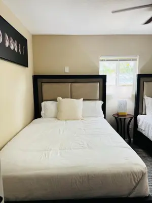 a bedroom with a large bed with white sheets at The Maze House Pool Theatre Room in San Bernardino