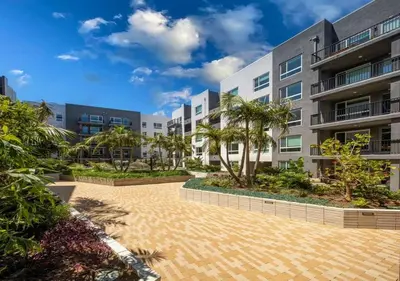an apartment building with a courtyard with palm trees at Pacific Paradise 10 Min from Disneyland With Pool & GYM in Santa Ana