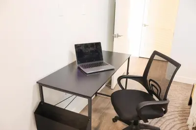 a laptop computer sitting on a black desk with a chair at Pacific Paradise 10 Min from Disneyland With Pool & GYM in Santa Ana