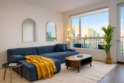 a living room with a blue couch and a table at Premium Stay 10 Min From Disneyland With Pool & GYM in Santa Ana