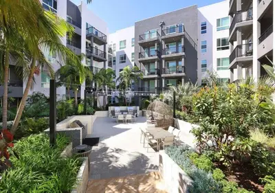 a courtyard in a building with chairs and palm trees at Stunning Haven with Pool Gym Parking Close to Disneyland in Santa Ana