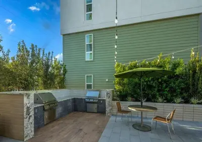 a patio with a table and an umbrella next to a building at Stunning Haven with Pool Gym Parking Close to Disneyland in Santa Ana