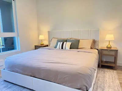 a large white bed in a bedroom with two lamps at Stunning Haven with Pool Gym Parking Close to Disneyland in Santa Ana