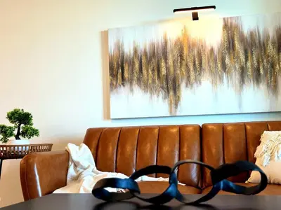 a brown leather couch with a painting on the wall at Luxury Haven 10 Min From Disneyland With Pool & GYM in Santa Ana