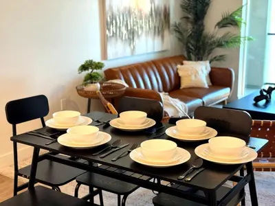 a black table with white dishes on it in a living room at Luxury Haven 10 Min From Disneyland With Pool & GYM in Santa Ana