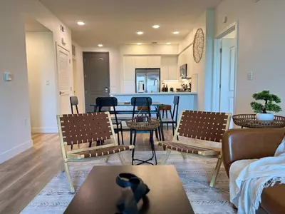a living room with chairs and tables and a kitchen at Luxury Haven 10 Min From Disneyland With Pool & GYM in Santa Ana