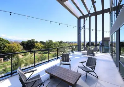 a patio with chairs and a wooden table on a balcony at Modern Retreat 10 Min from Disneyland With Pool & Gym in Santa Ana