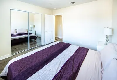 a bedroom with a large bed and a mirror at Spacious 5BR 3BA Home with Free Parking and WiFi 10 Minutes to Downtown LA Perfect for Large Groups in Los Angeles