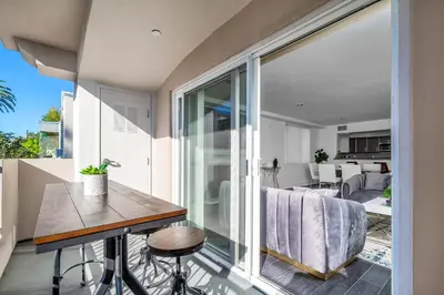 a kitchen and living room with a balcony with a table at Amazing & Spacious in Heart of Santa Monica- Easy Access to ALL Tourist attractions in Los Angeles
