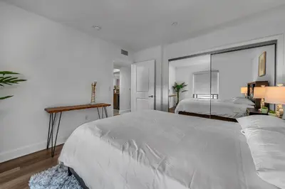 a white bedroom with two beds and a mirror at Amazing Spacious Unit in Heart of LA- Melrose district in Los Angeles