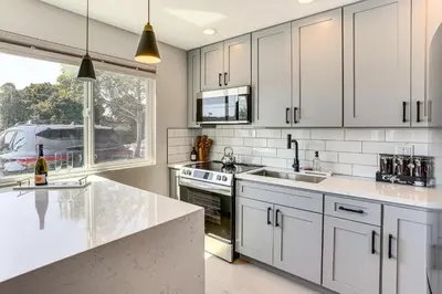 a kitchen with white cabinets and a large window at Newly Updated! Commuter-Friendly Anaheim Home in Anaheim