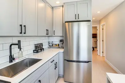 a kitchen with white cabinets and a stainless steel refrigerator at Newly Updated! Commuter-Friendly Anaheim Home in Anaheim