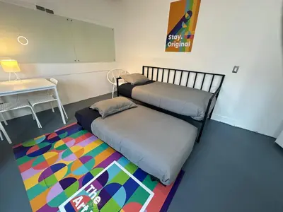 a room with two beds and a table and a rug at The Art Nook Private Rooms on Hollywood Blvd in Los Angeles
