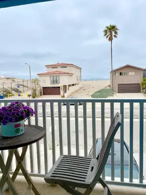 a table and a chair on a balcony with a beach at Luxury, Beach House, and quiet neighborhood in Oxnard