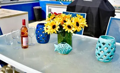 a table with a vase of yellow flowers and wine glasses at Luxury, Beach House, and quiet neighborhood in Oxnard