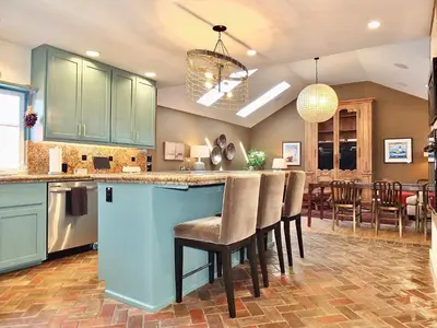 a kitchen with blue cabinets and a bar with chairs at Naples Luxury Retreat - 2 BDR Walk to Beach Dining & Shops in Long Beach