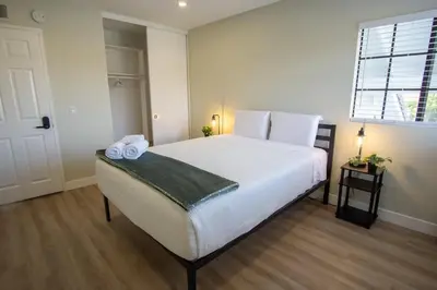 a bedroom with a bed with white sheets and a window at CA2 House SoCal Oasis Newly Renovated Game Room in La Palma