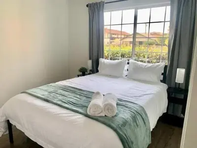 a bedroom with two towels on a bed with a window at CA5 House Cozy 3BR in Azusa in Azusa