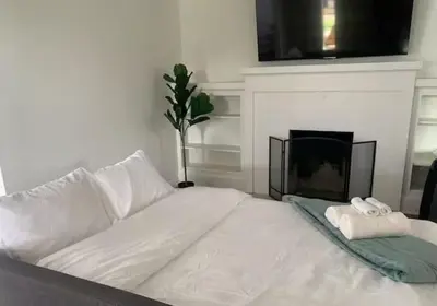 a white bed in a room with a fireplace at CA5 House Cozy 3BR in Azusa in Azusa