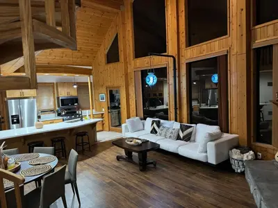 a living room with a white couch and a kitchen at Lakefront Oasis in Fawnskin