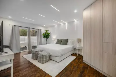 a white bedroom with a bed and a television at Shirley Lane in Los Angeles