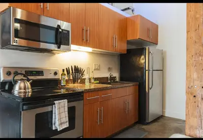 a kitchen with stainless steel appliances and wooden cabinets at 1400 square foot Arts District Warehouse Loft 1 bedroom 1 bathroom in Los Angeles