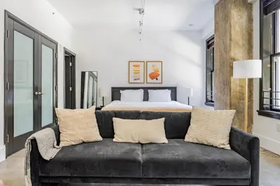 a black couch in a bedroom with a bed at Blueground Historic Core view nr Grand Park LAX-1424 in Los Angeles