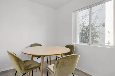 a table and chairs in a room with a window at Blueground Melrose pool nr Griffith Park LAX-1399 in Los Angeles