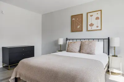 a white bedroom with a bed and a black dresser at Blueground Melrose pool nr Griffith Park LAX-1399 in Los Angeles