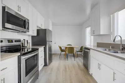 a kitchen with white cabinets and a table with chairs at Blueground Melrose pool nr Griffith Park LAX-1399 in Los Angeles