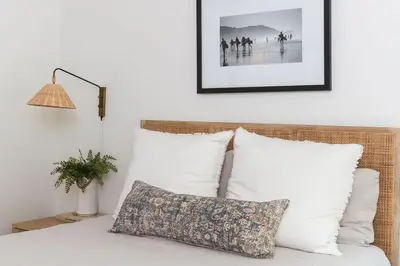a bed with white pillows and a picture on the wall at Naples Island Stunning Ocean Cottage By the Beach in Long Beach