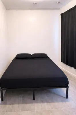 a black bed in a white room with a window at La Cienega Soul in Los Angeles
