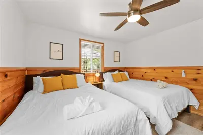 two beds in a room with a ceiling fan at Navigate Stays 5BR Group Lodge Near Mountain & Fun in Big Bear Lake