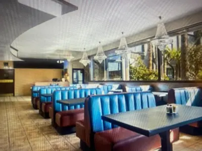 a dining room with blue chairs and tables at Hiltop Hotel in Bakersfield