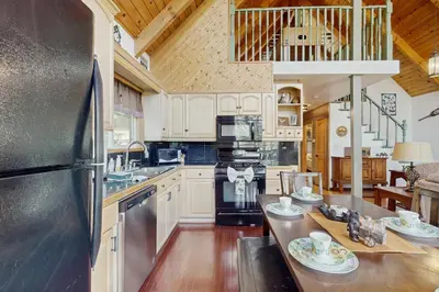 a kitchen with white cabinets and a stainless steel refrigerator at Cedar Glen Hideaway in Lake Arrowhead