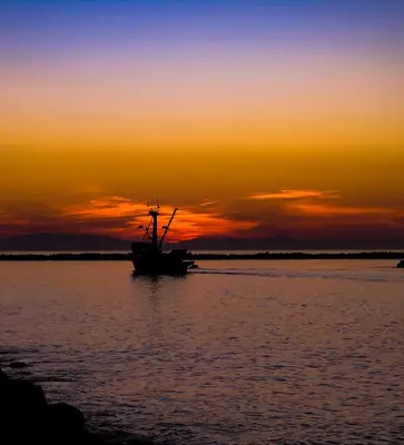 a boat in the water at sunset at Silverstrand Beach House in Oxnard