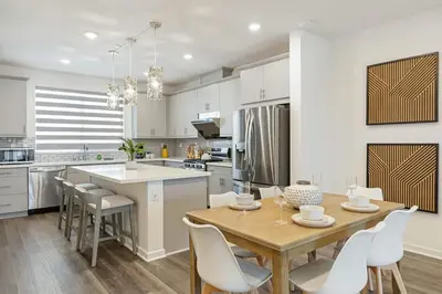 a kitchen with a wooden table and white cabinets at Modern Townhouse Near Disneyland & OC Beaches in Covina